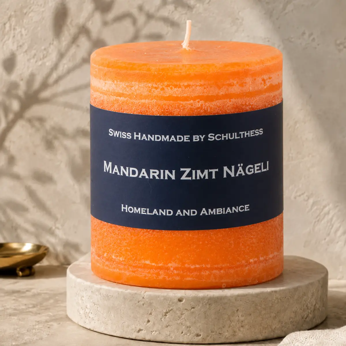 Schulthess Duftkerze Mandarine · Zimt · Nägeli in Orange auf hellem Travertinsockel