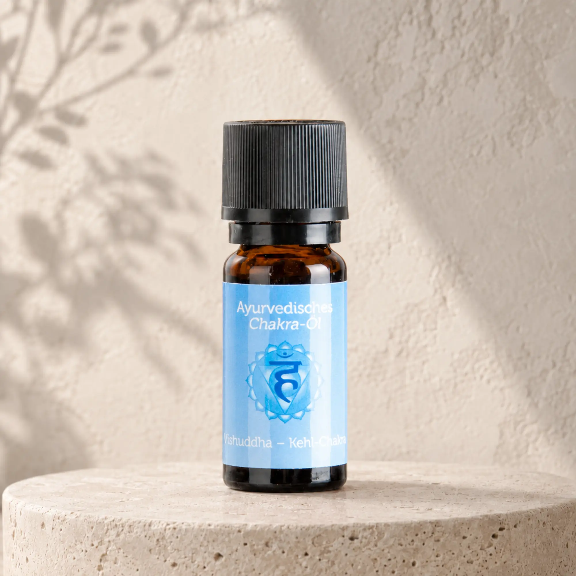 Berk ayurvedisches Chakra-Öl Vishuddha für das Kehlchakra auf hellem Steinpodest