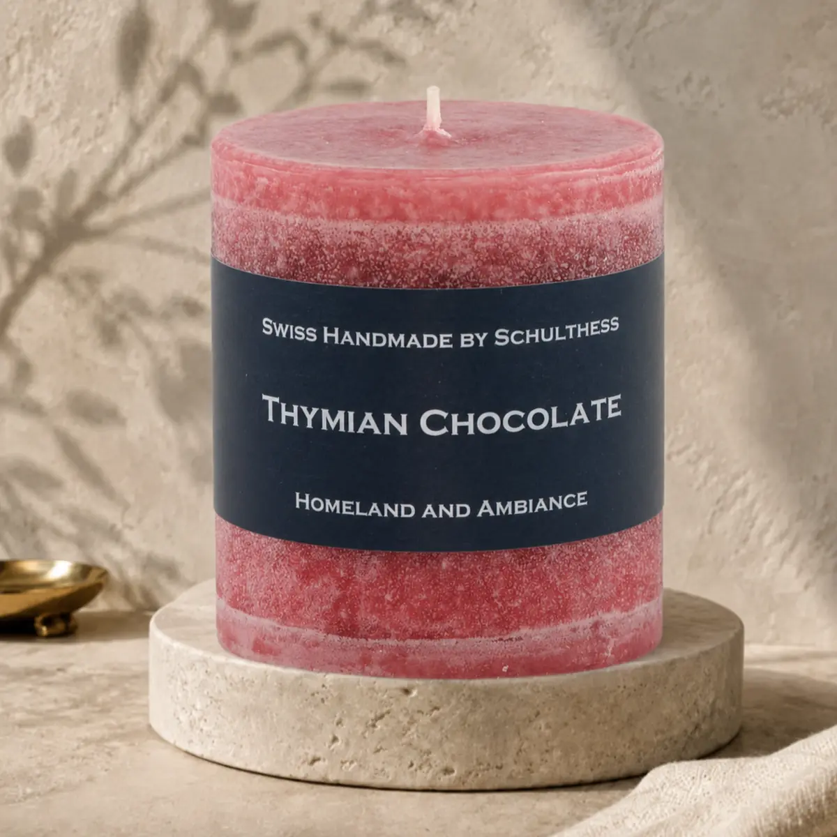 Schulthess Duftkerze Thymian Chocolate auf einem Travertinteller