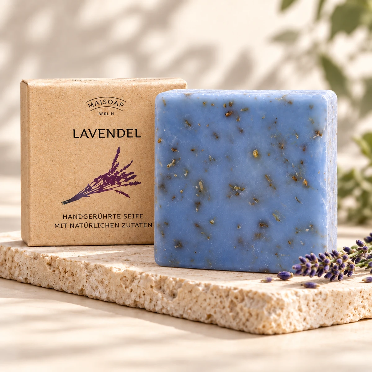 Blaue Maisoap Lavendelseife mit Verpackung und Lavendelzweigen auf heller Steinplatte