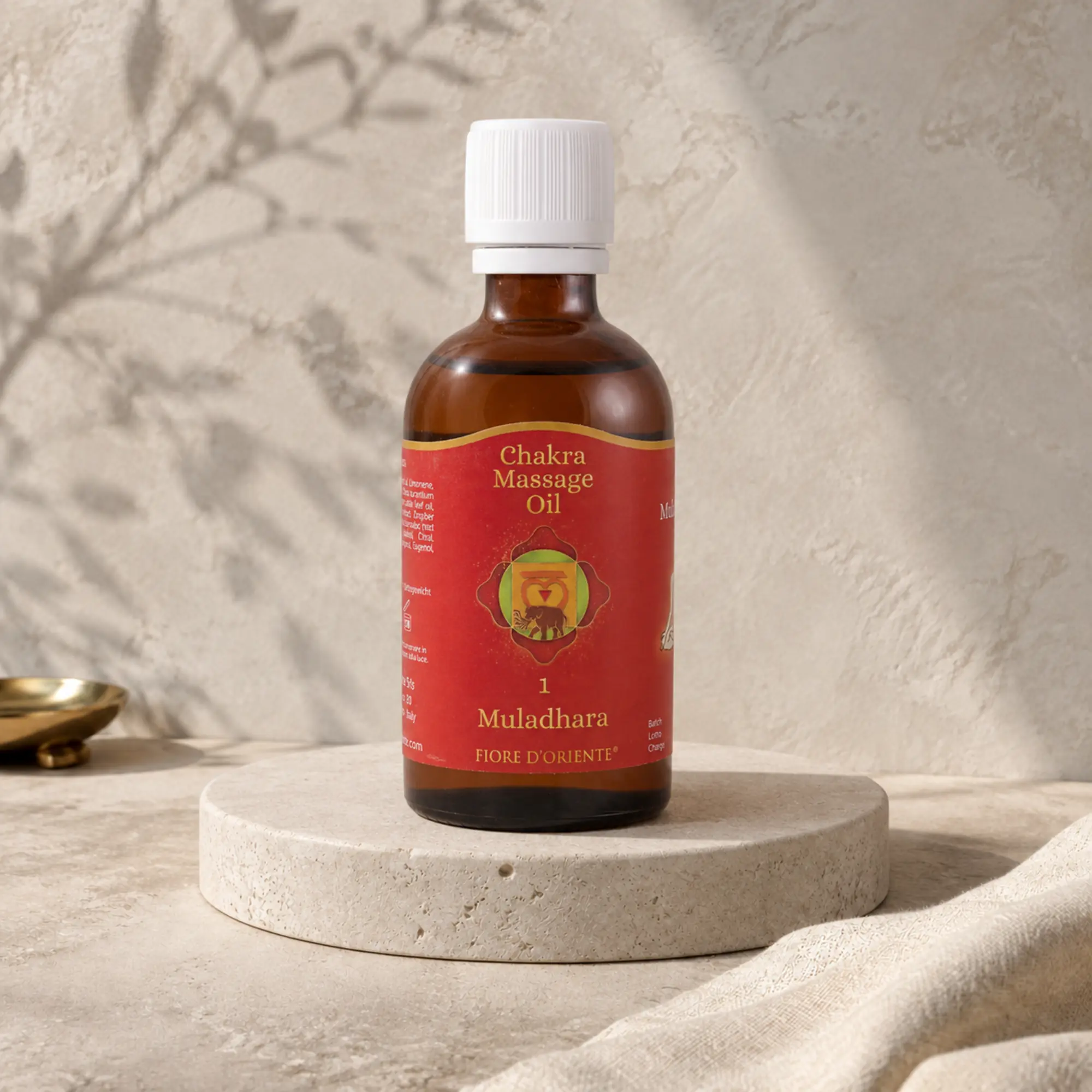 Muladhara Wurzel Chakra Massageöl von Berk, 100 ml, auf hellem Travertin-Podest