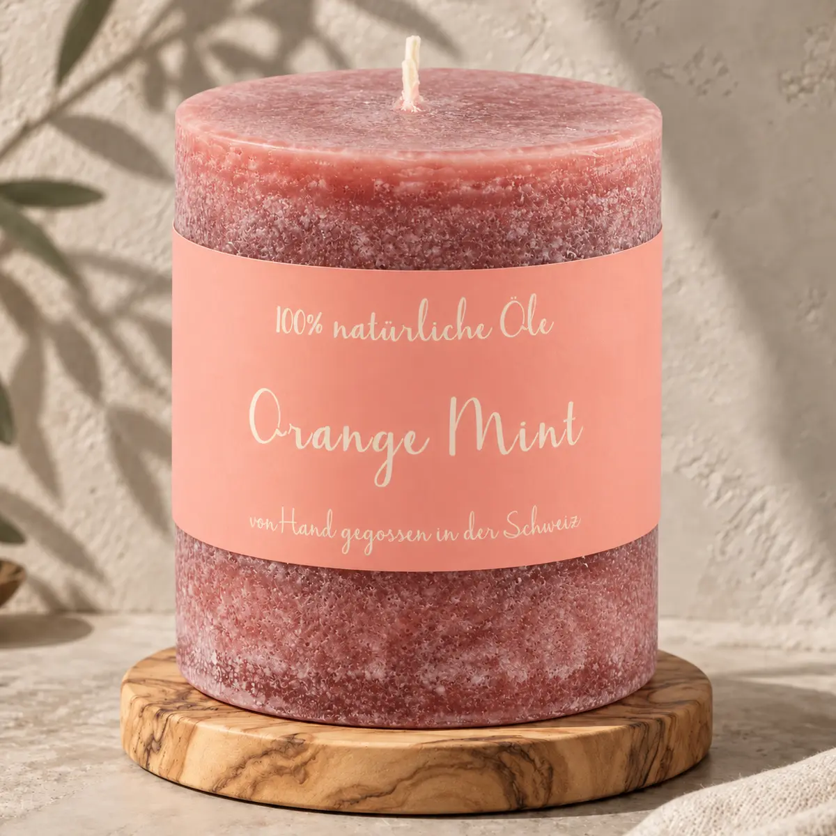 Dunkelrosafarbene Schulthess Duftkerze Orange Mint aus 100 % natürlichen Ölen auf einem Holzsockel