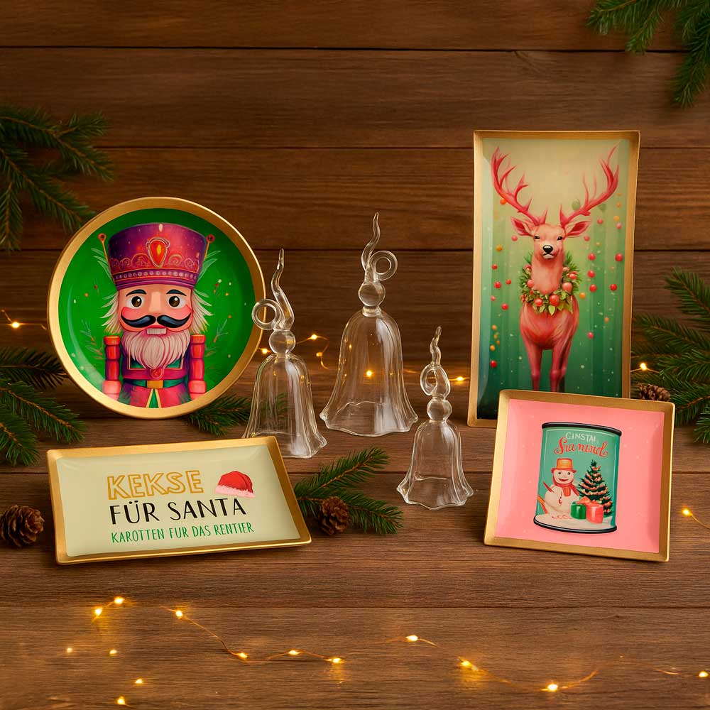 Weihnachtliche Glasteller Love Plates von Gift Company mit festlichen Motiven wie Nussknacker, Rentier und Schneemann, dekoriert mit Tannenzweigen, Zapfen und Lichterkette.