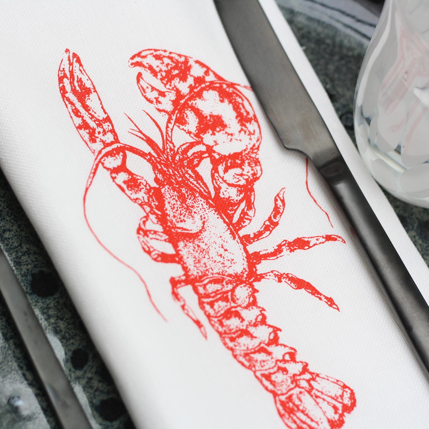 Frohstoff Serviette Hummer in Rot aus Halbleinen mit maritimem Handsiebdruck auf gedecktem Tisch – handbedruckte Stoffserviette aus Hamburg.