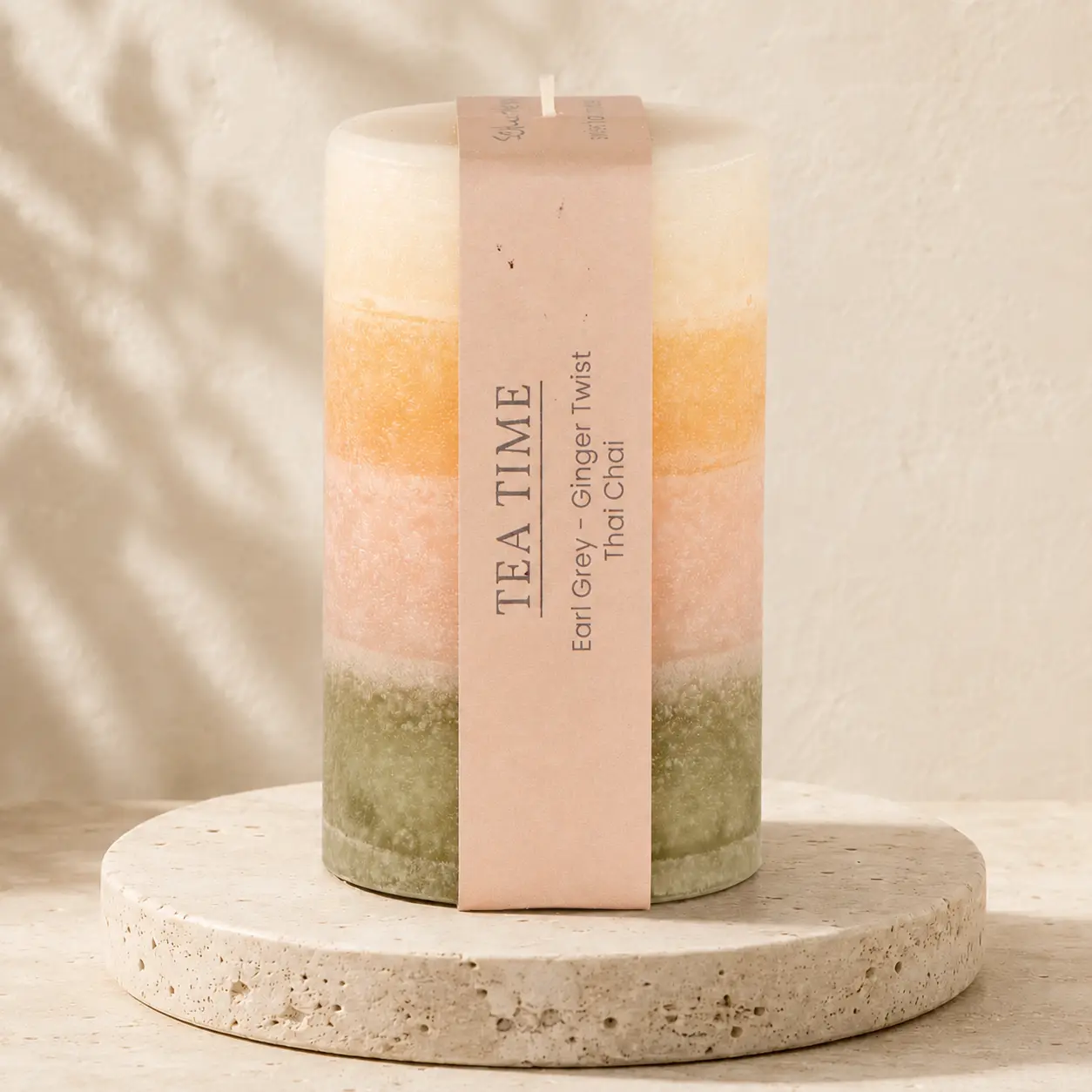 Runde Schulthess Duftkerze Tea Time in Creme, Apricot, Rosé und Olivgrün auf Travertin
