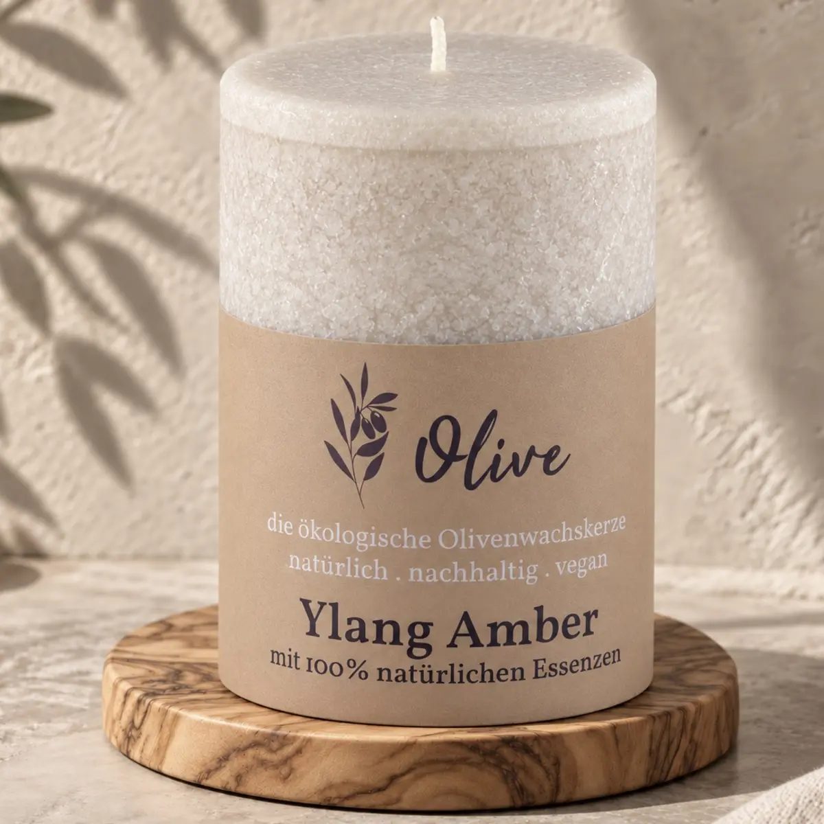 Schulthess Olivenwachskerze Ylang Amber auf einem runden Holzteller