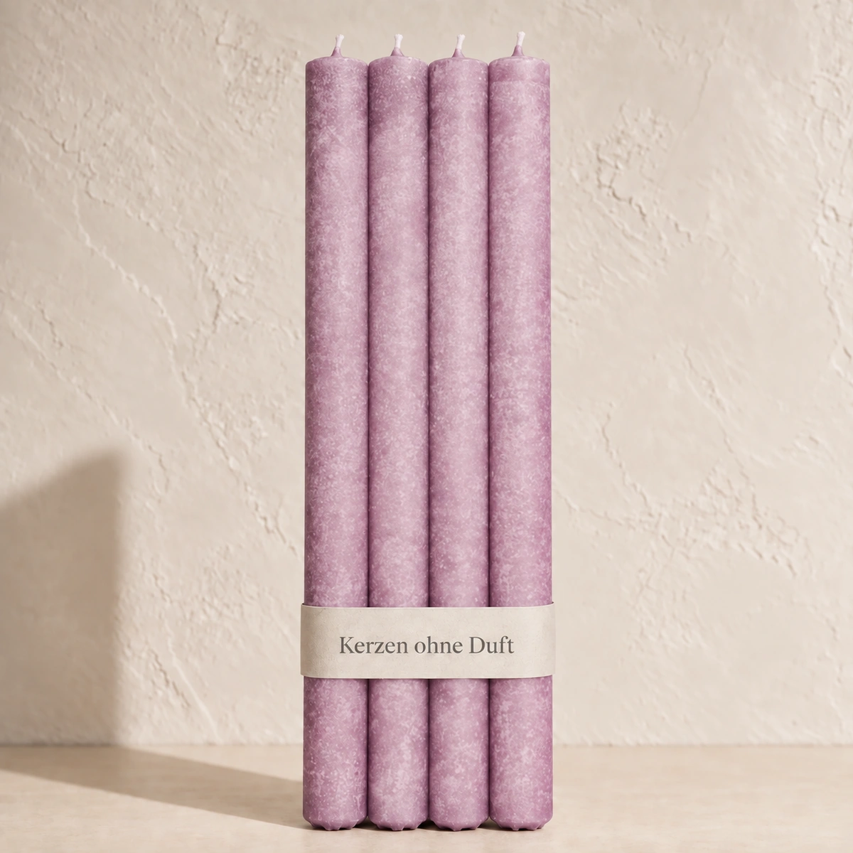 Vier Schulthess Stabkerzen in Rose Noir mit beiger Banderole „Kerzen ohne Duft“ vor einer hellen, warmen Wand.