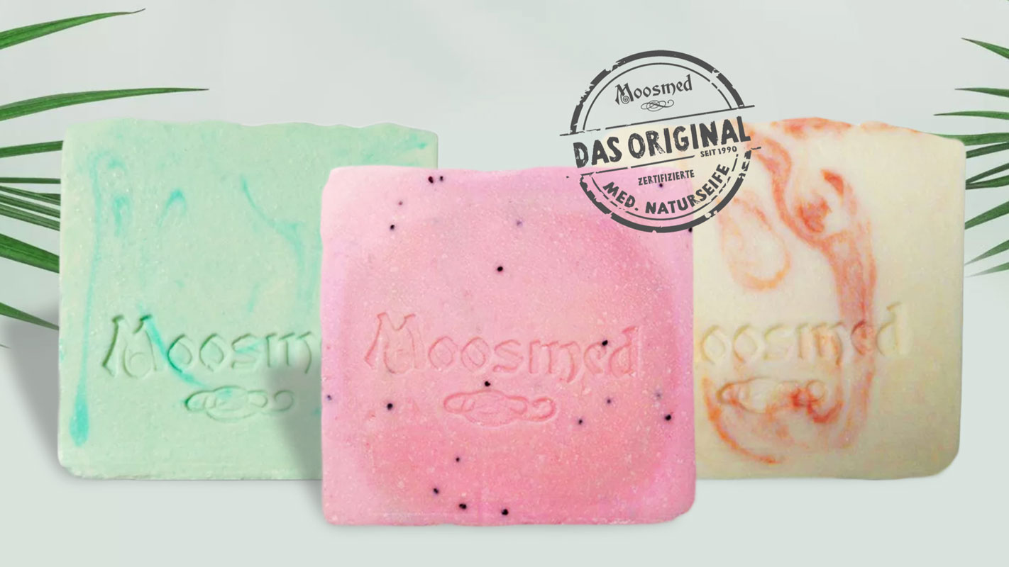 Moosmed Natural Cosmetics Drei bunte Moosmed Naturseifen in Grün, Rosa und Creme mit Logo-Prägung. Handgemachte, zertifizierte medizinische Seifen – pflegend, natürlich und nachhaltig.