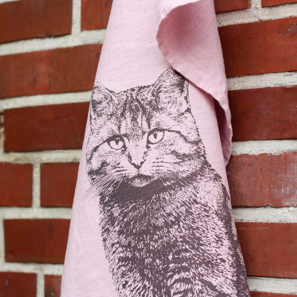 Frohstoff Geschirrtuch Wildkatze in Rosa aus Leinen mit handgedrucktem Katzenmotiv vor Backsteinwand – handgefertigtes Küchentextil aus Hamburg.