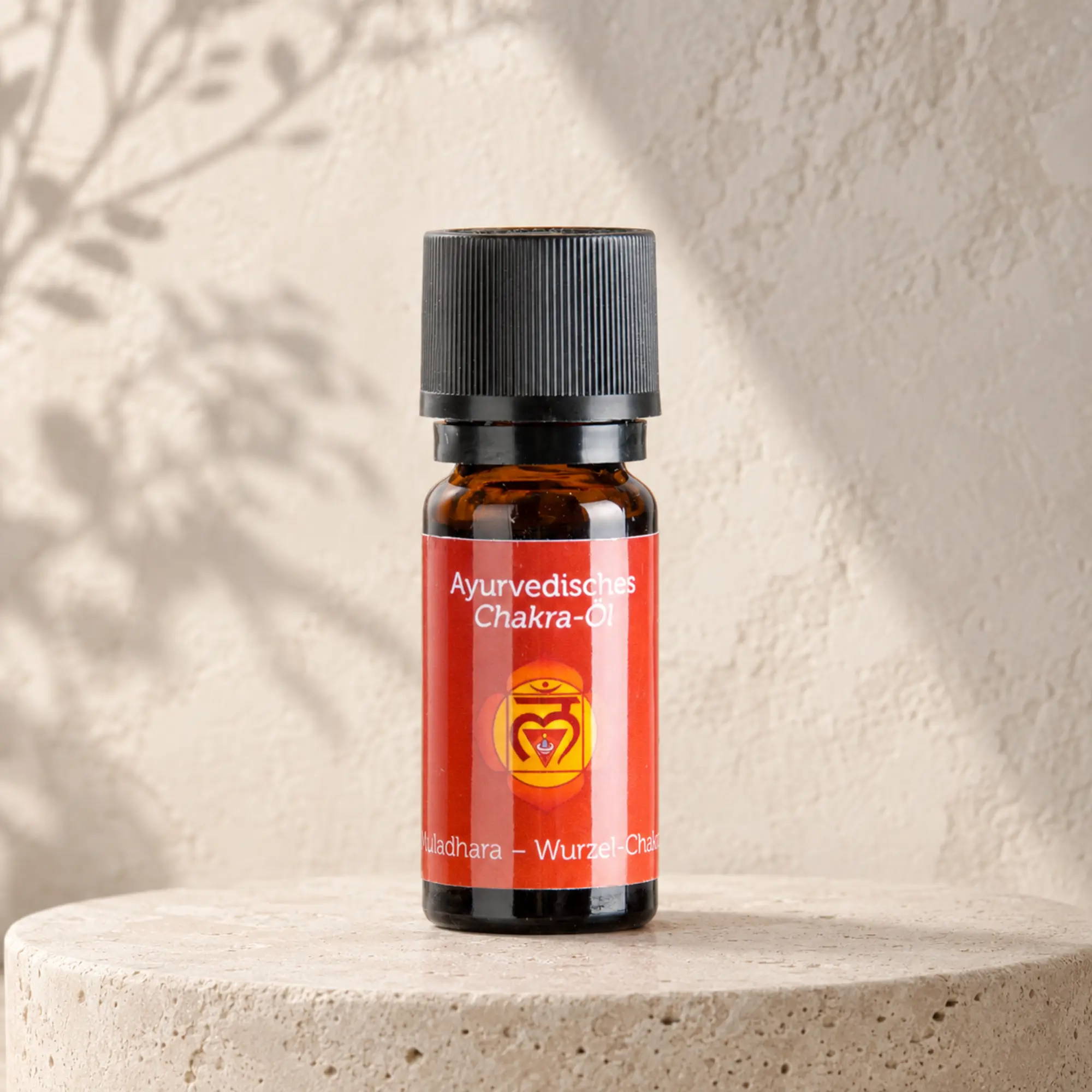 Berk ayurvedisches Chakra-Öl Muladhara für das Wurzelchakra auf hellem Steinpodest