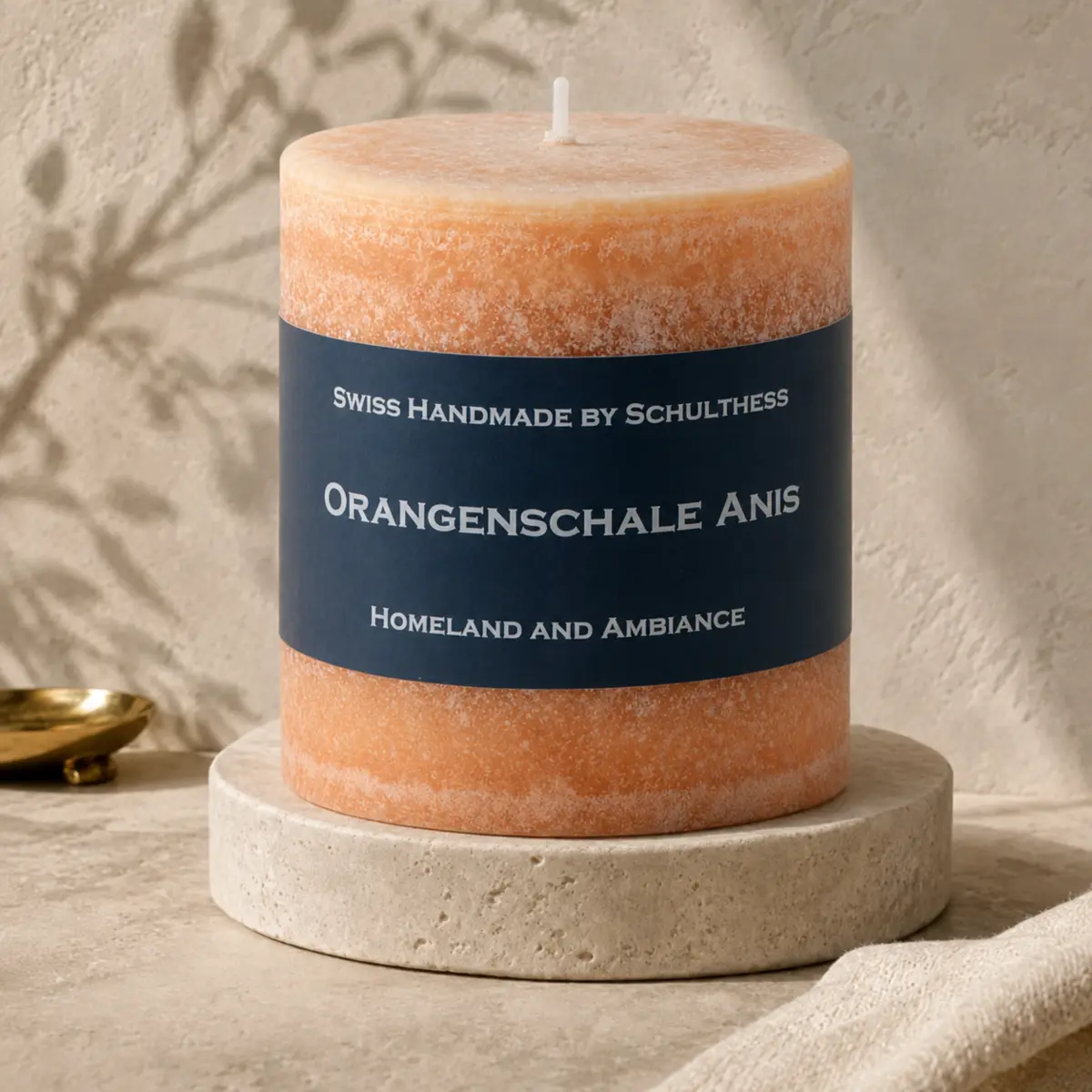 Schulthess Duftkerze Orangenschale & Anis in warmem Orange auf hellem Travertinsockel