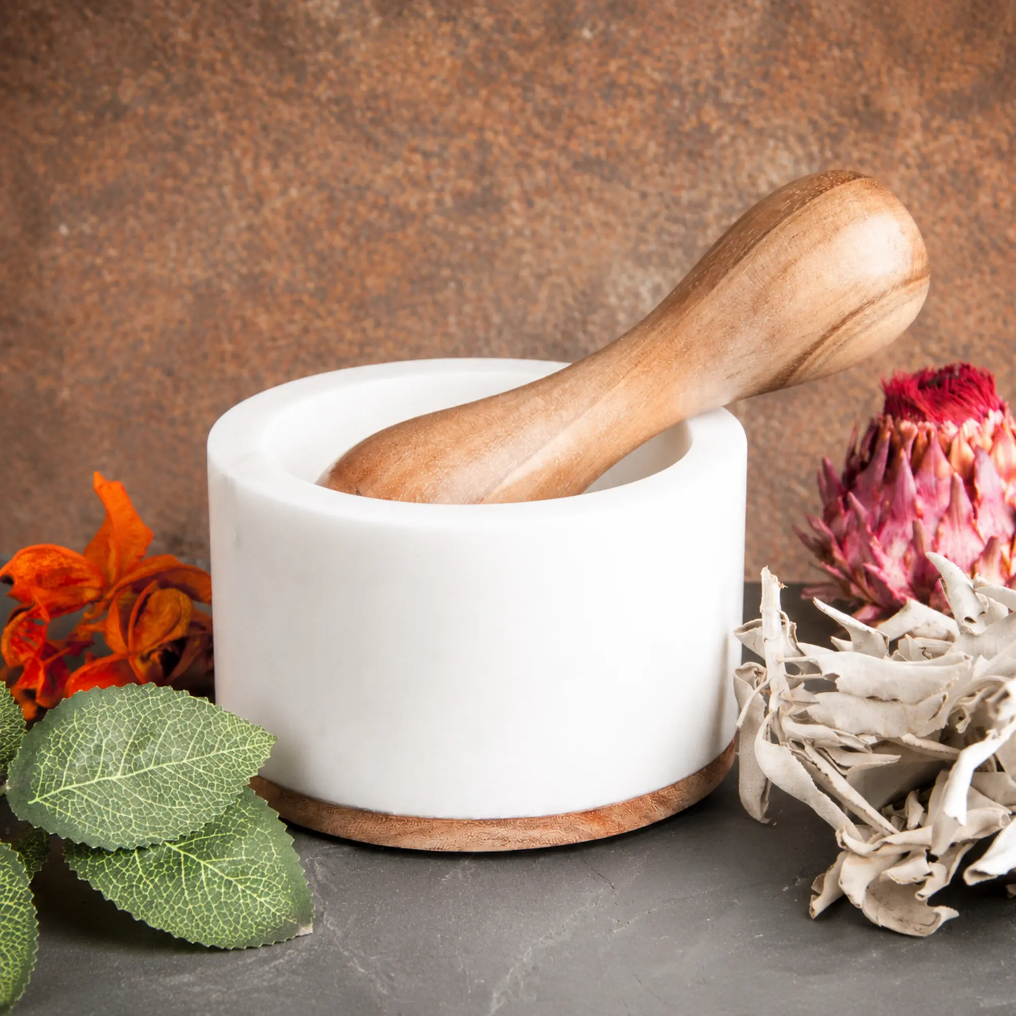 Marmormörser mit Holzstößel, Kräutern und Blüten
