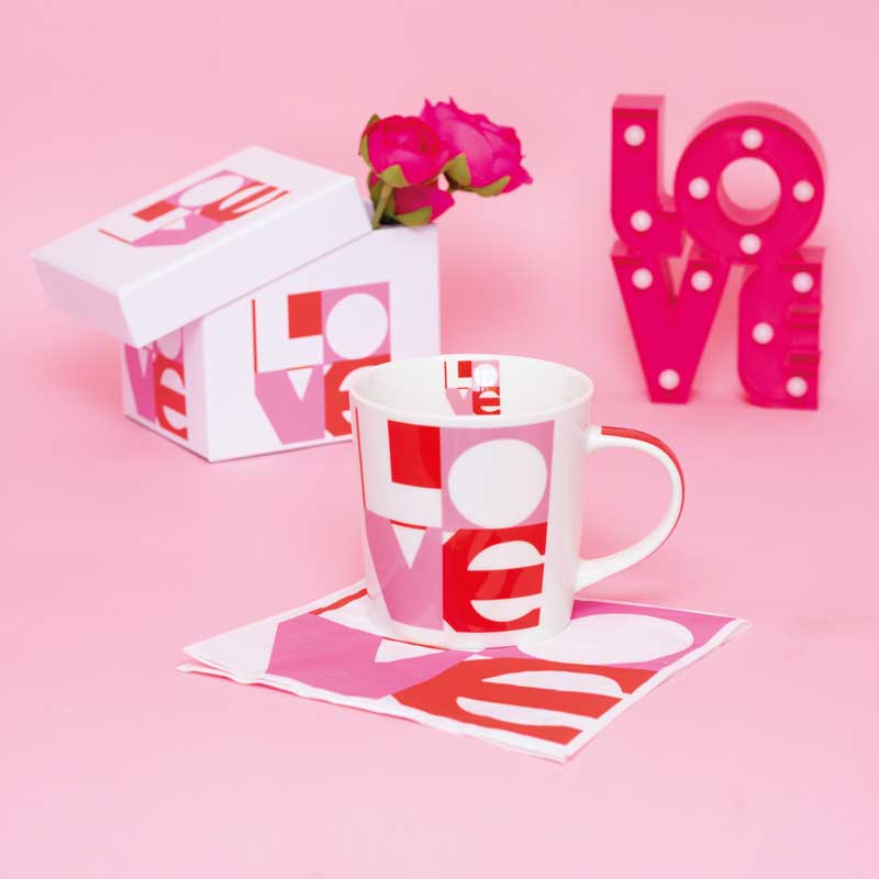 Moderne Porzellantasse Love Graphic von PPD in kräftigem Pink, Rot und Weiß, kombiniert mit passender Geschenkbox und Serviette – ein stilvolles Präsent für romantische Anlässe.