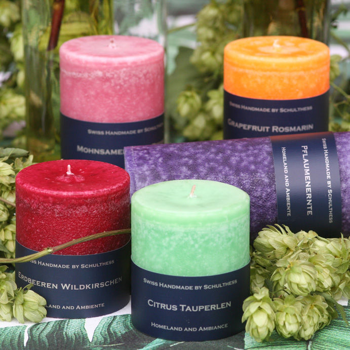 Bunte Schulthess Duftkerzen aus der Duftwelt Citrus & Früchte in den Sorten Grapefruit Rosmarin, Erdbeeren Wildkirschen, Pflaumenernte, Mohnsamen und Citrus Tauperlen – handgefertigte Kerzen mit fruchtig-frischen Düften, dekoriert mit Hopfen und Blättern.