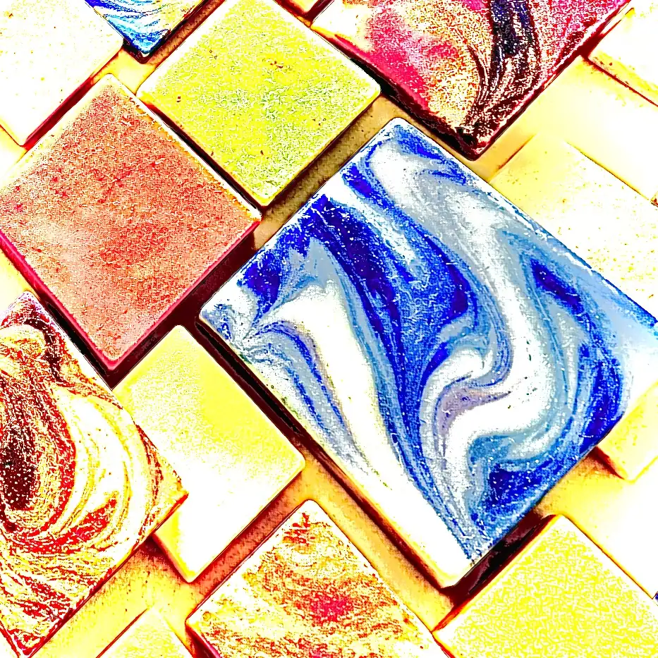 Künstlerische Nahaufnahme diagonal angeordneter Maisoap-Seifen in kräftigem Gelb, Rot und Blau mit ausdrucksstarken Marmorierungen.