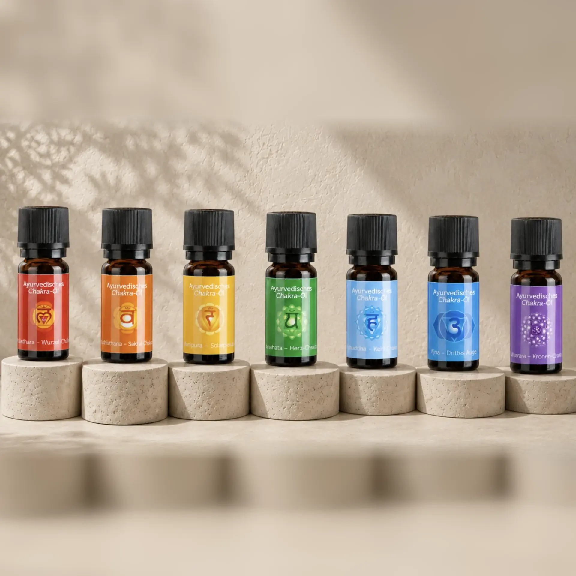 Sieben ayurvedische Chakra-Öle von Berk in den Farben der sieben Energiezentren auf hellen Travertinsockeln.