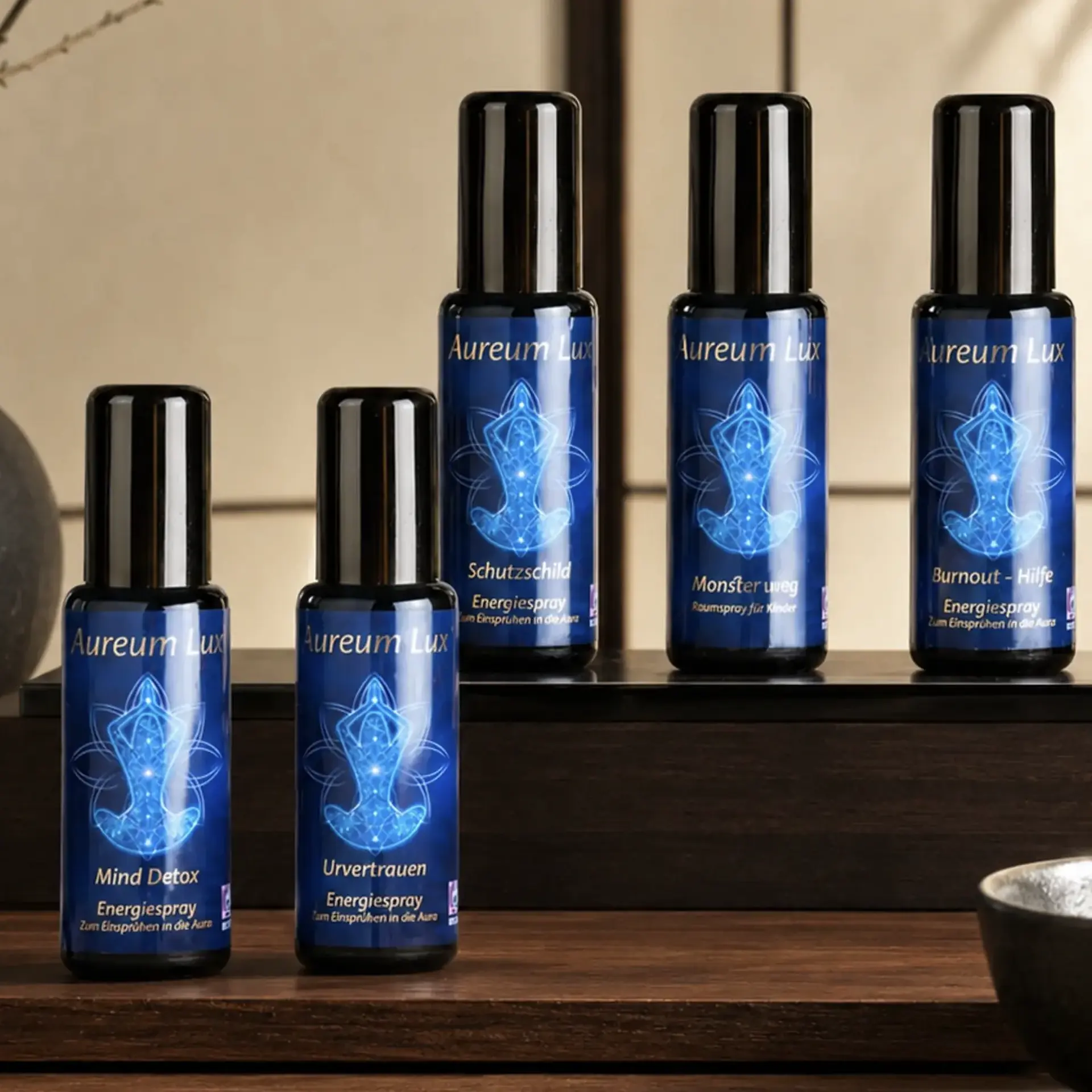 Fünf Aureum Lux Energiesprays von Berk auf dunklen Podesten in warmer Zen-Atmosphäre.