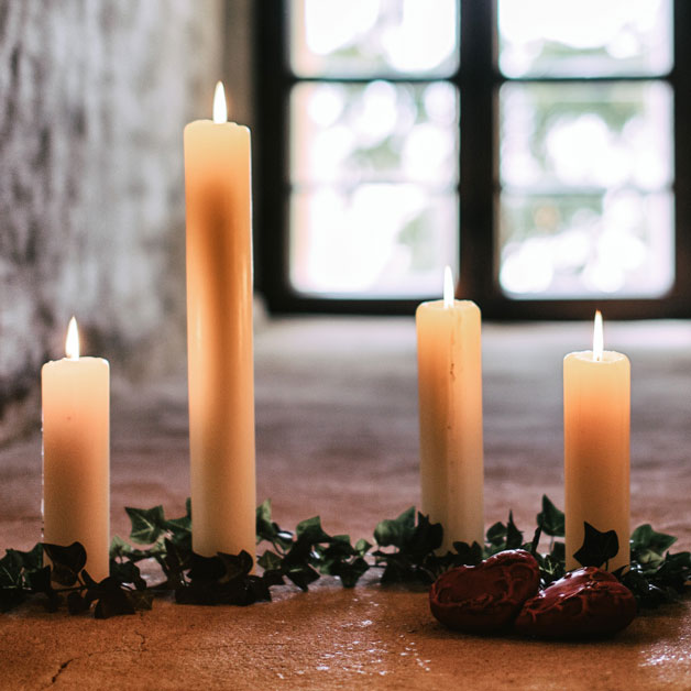 Schulthess Stabkerzen ohne Duft, elegant arrangiert mit Efeu und roten Dekoelementen. Hochwertige, handgefertigte Kerzen für stilvolle Atmosphäre und natürliches Licht.