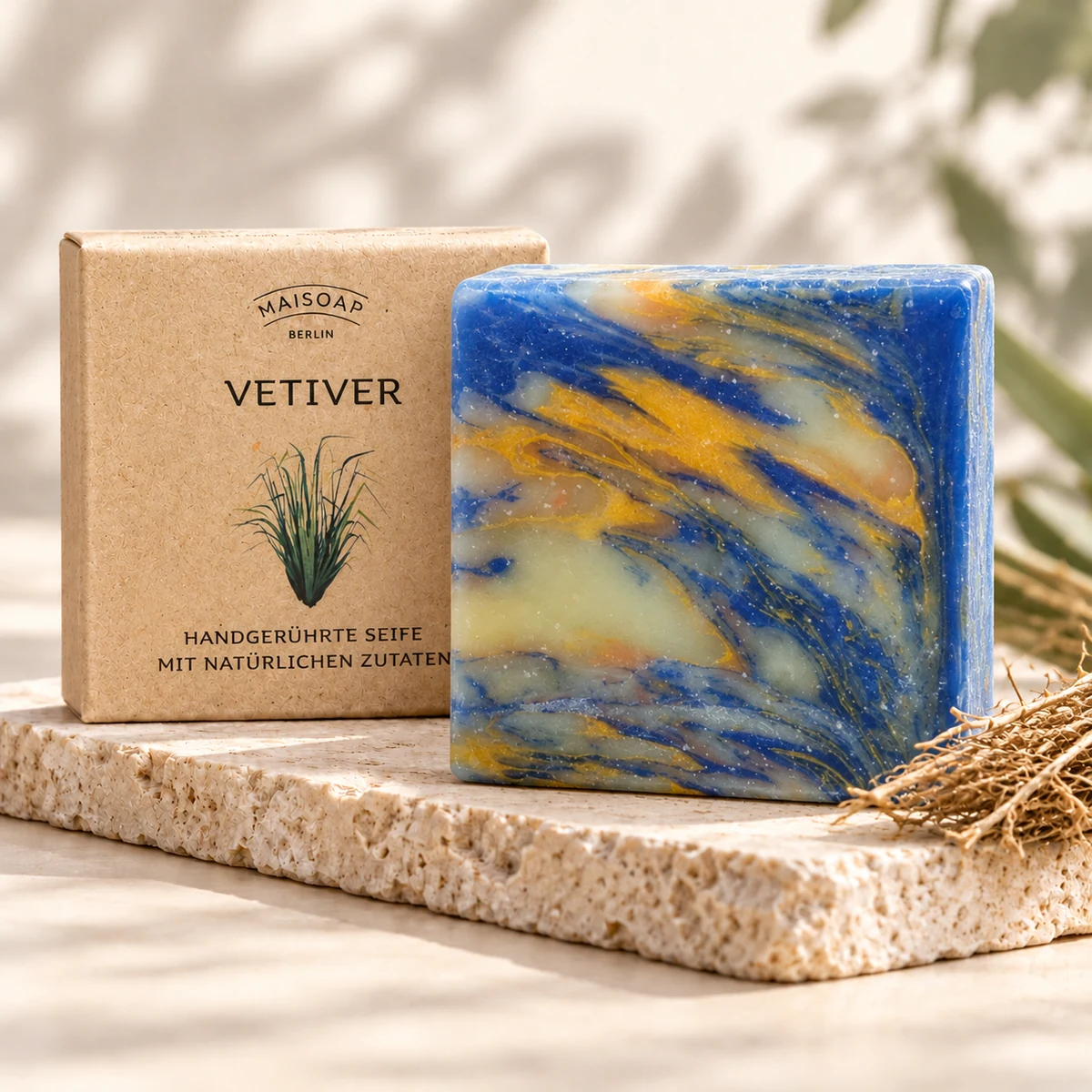 Blau-gelb marmorierte Maisoap Vetiver-Seife mit Verpackung und Vetiverwurzeln auf heller Steinplatte