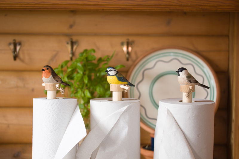 Wildlife Garden Küchenrollenhalter – handgeschnitzte Holzvögel auf Holzständern als charmante Tisch- und Küchendekoration mit naturgetreuem skandinavischem Design.