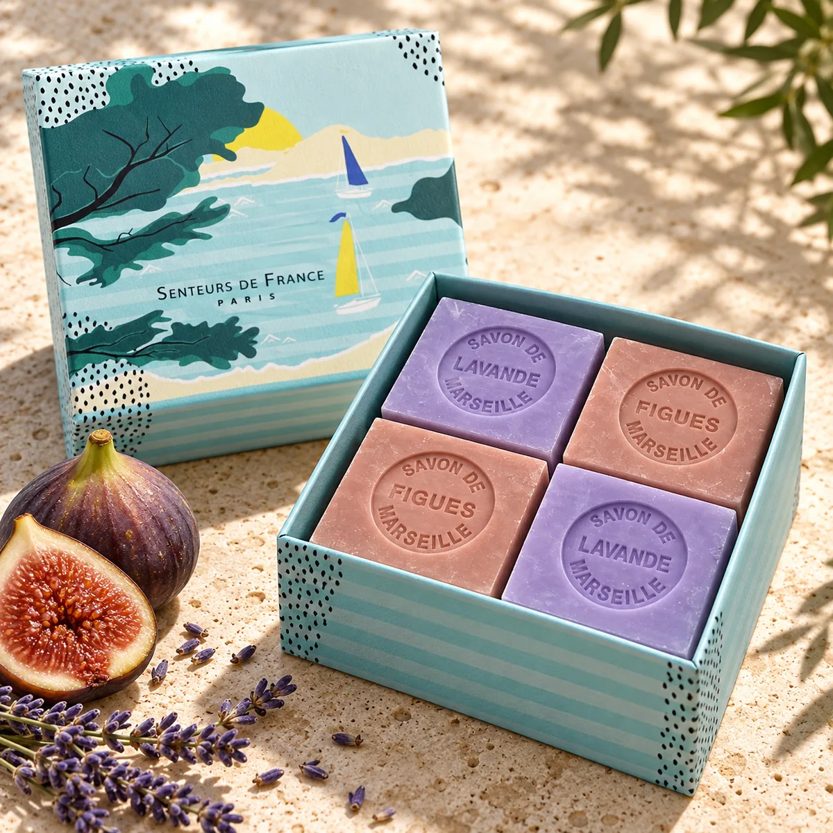 Vier Würfelseifen Feige und Lavendel von Senteurs de France in einer türkisfarbenen Geschenkbox mit mediterranem Küstenmotiv.