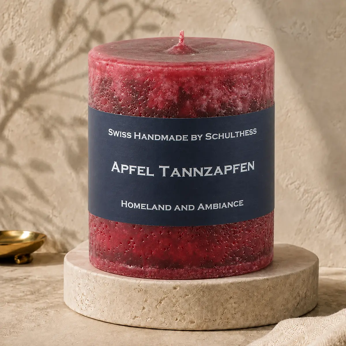 Schulthess Duftkerze Apfel Tannzapfen auf einem Travertinteller