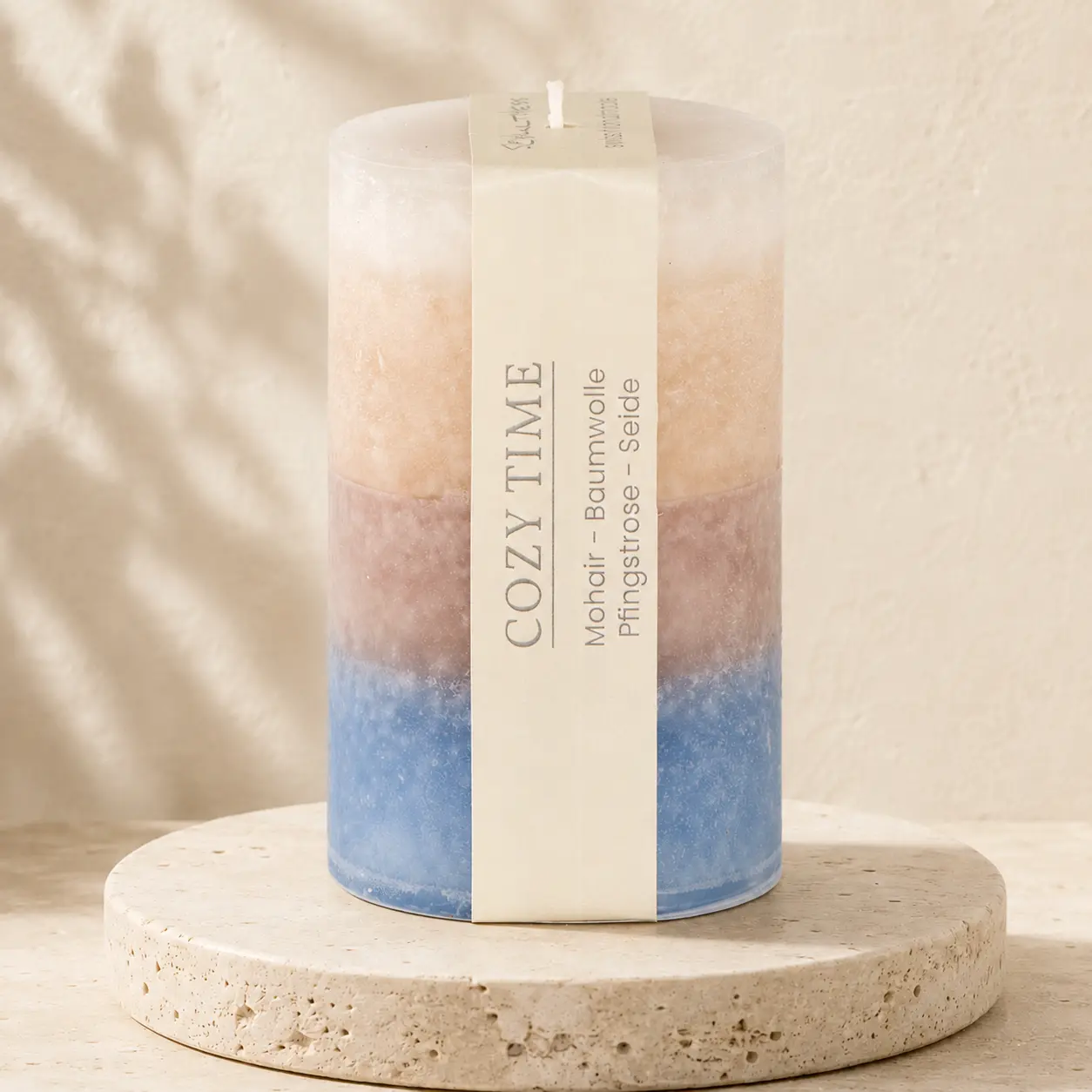 Runde Schulthess Duftkerze Cozy Time in Creme, Beige, Mauve und Blau auf hellem Travertin