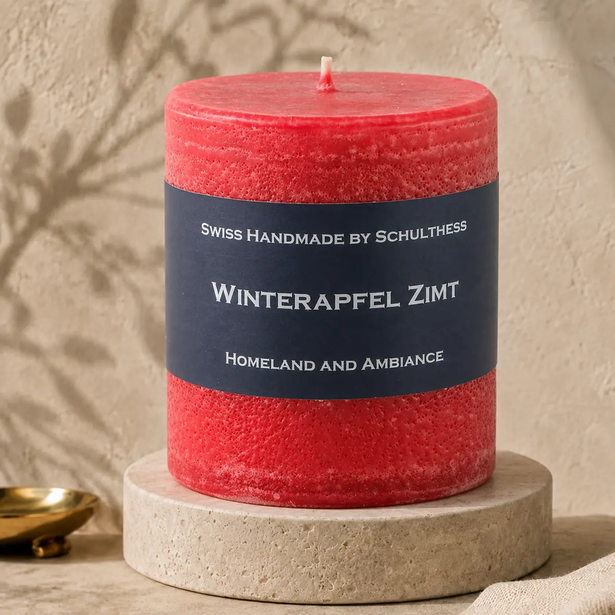 Schulthess Duftkerze Winterapfel Zimt auf einem Travertinteller