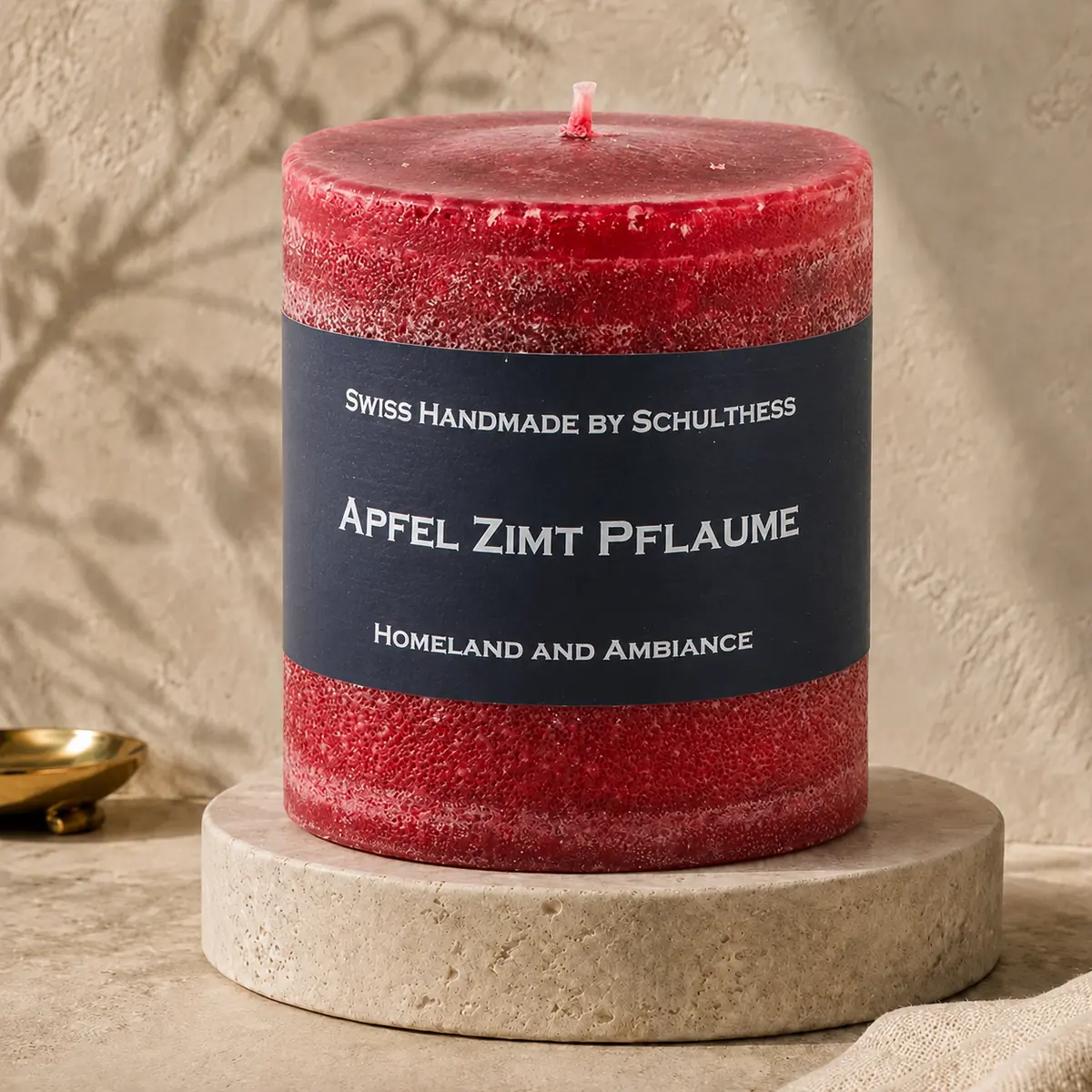 Schulthess Duftkerze Apfel Zimt Pflaume auf einem Travertinteller