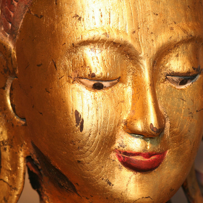 Nahaufnahme des Gesichts eines großen burmesischen Königsbuddha, vergoldete Oberfläche mit Patina, sanfter Ausdruck und feine Handbemalung.
