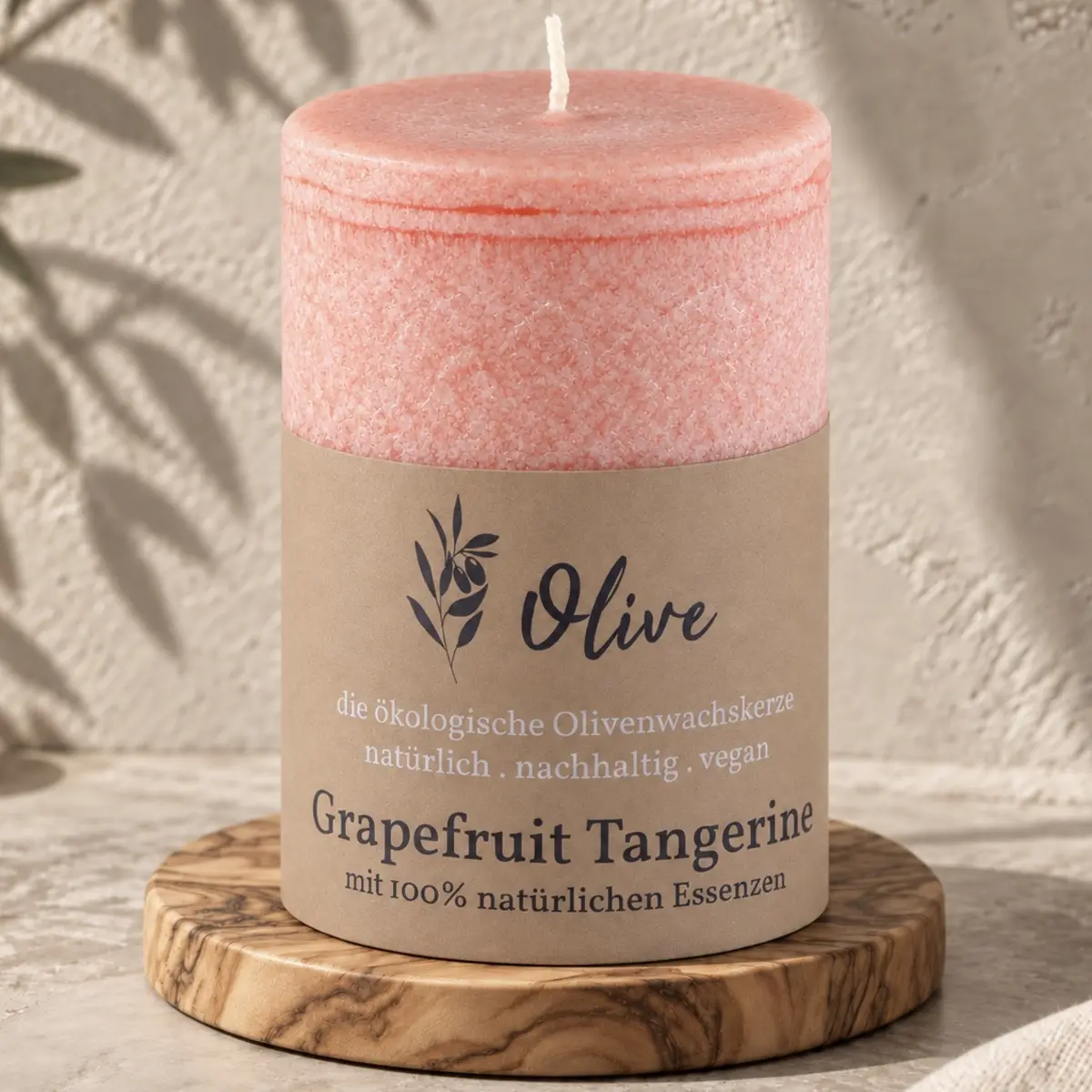 Schulthess Olivenwachskerze Grapefruit & Tangerine auf einem runden Holzteller