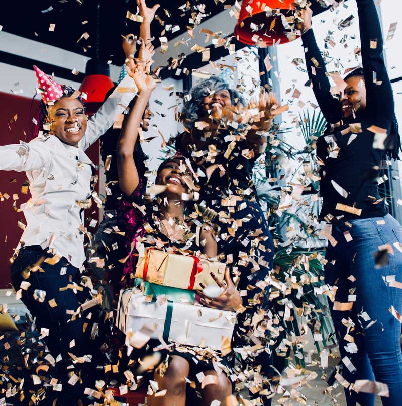 Freunde feiern eine fröhliche Party mit goldfarbenem Konfetti und Geschenken. Perfektes Bild für Geschenkideen, Feier, Geburtstag oder besondere Anlässe.