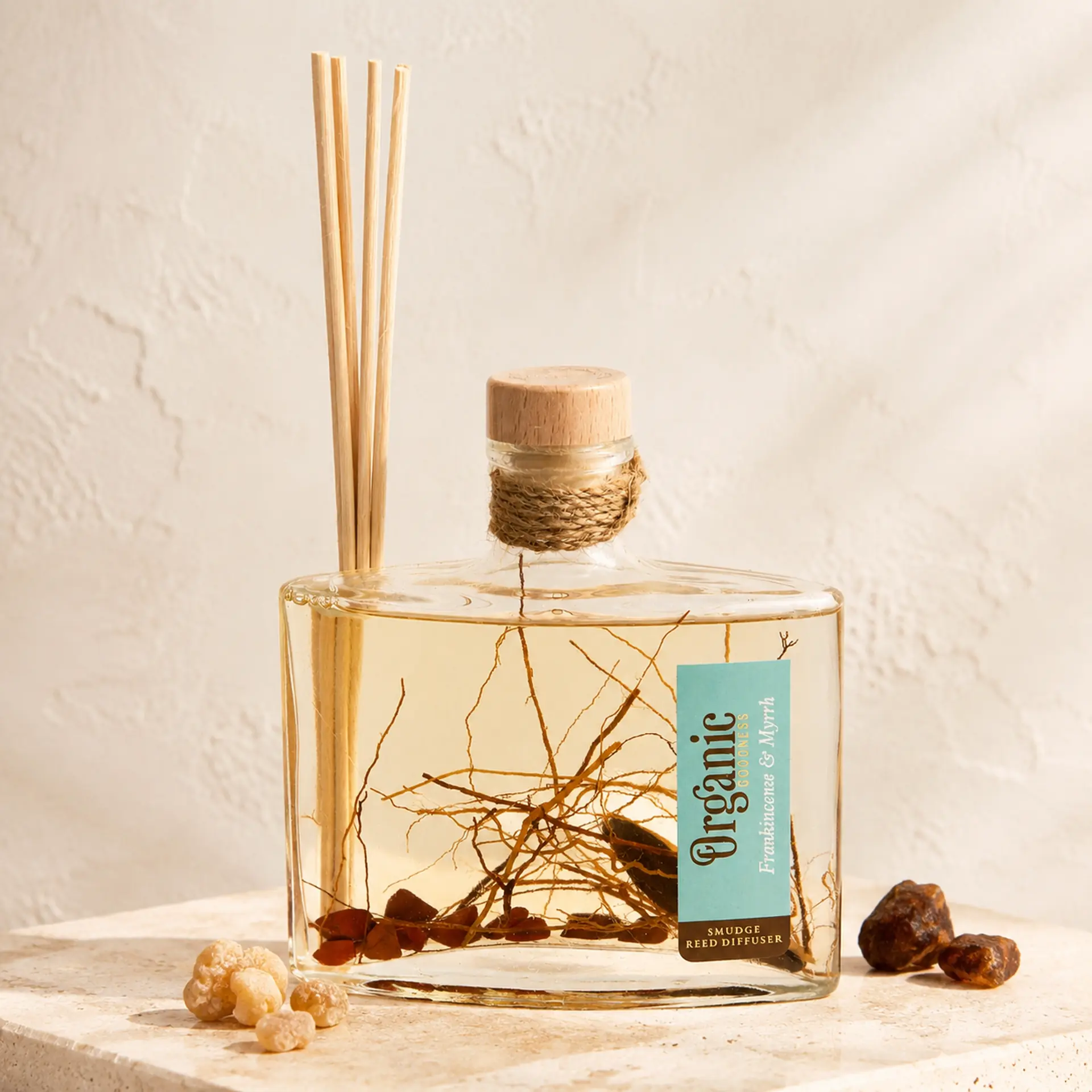 Organic Goodness Reed Diffuser Frankincense & Myrrh mit hellen und dunklen Räucherharzen auf Travertin.