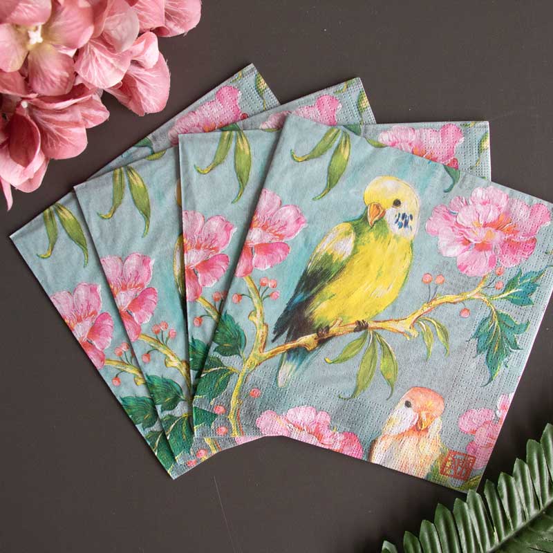 PPD Servietten mit farbenfrohem Papageien- und Blumenmotiv in Rosa und Grün, dekorativ arrangiert mit Hortensien – elegante Tischdeko für Frühling und Sommer.