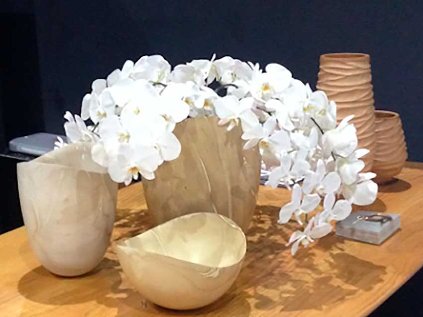 Dekorative Dokoschalen aus hellem Mangoholz in verschiedenen Größen, auf einem Holztisch arrangiert, mit weißen Orchideen als stilvoller Blickfang.