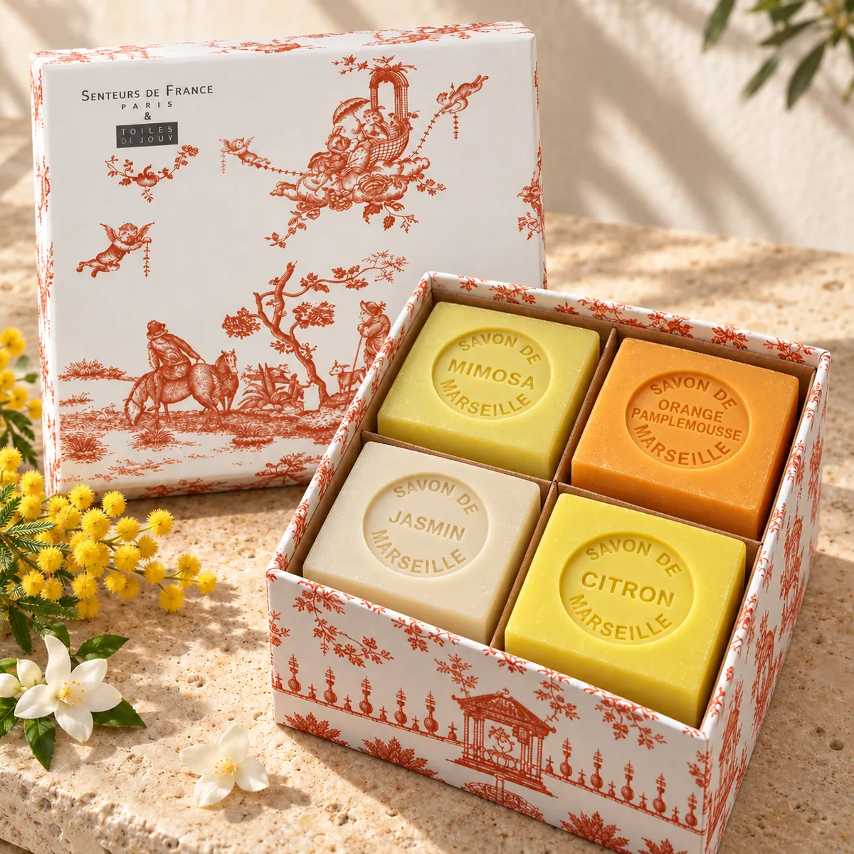 Senteurs de France Seifenset mit vier Würfelseifen in orange-weißer Toile-de-Jouy-Geschenkbox auf Travertin.